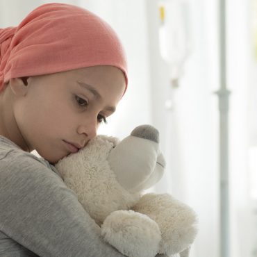 Mädchen mit Teddybär im Spitalbett